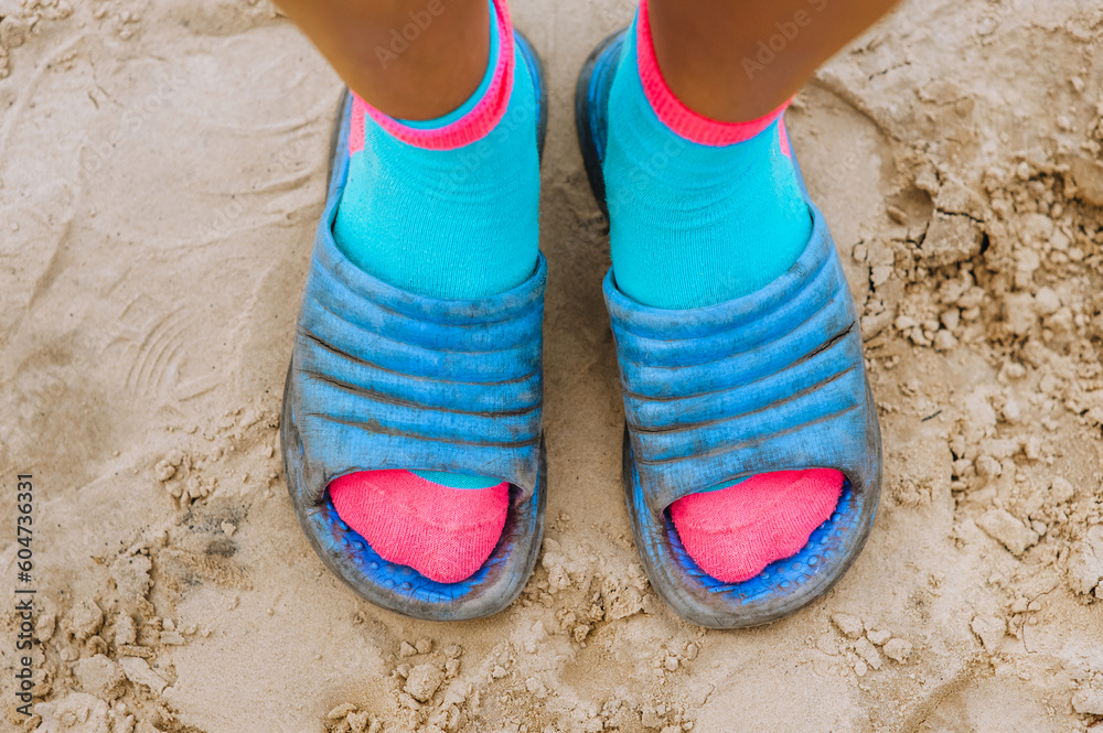 Naklejka premium A woman in blue sandals stands on the beach on the sand. Photography, portrait.