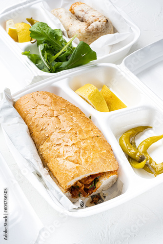 Chicken tantuni with loaf bread Turkish kebab, in plastic pack container delivery lunch box, on white stone table background