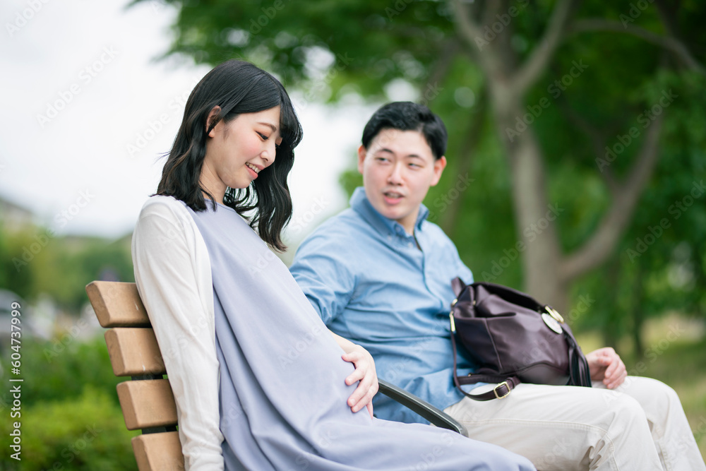 公園で休憩する妊婦と夫