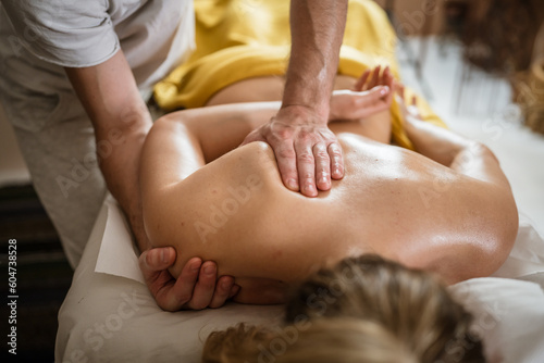 unknown woman enjoy shoulder and back massage at spa male therapist