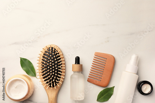 Flat lay composition with wooden hair brush and comb on white marble table, space for text