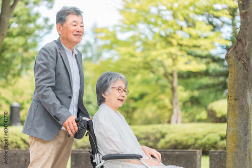 車椅子に乗って散歩する日本人の高齢者夫婦 