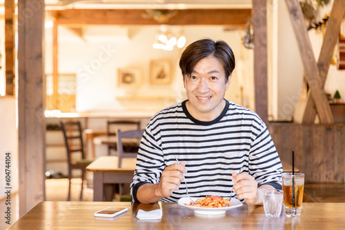 お昼休みにカフェやレストランでランチ・食事をするアジア人の男性 