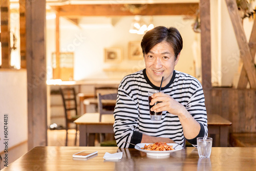 お昼休みにカフェやレストランでランチ・食事をするアジア人の男性 