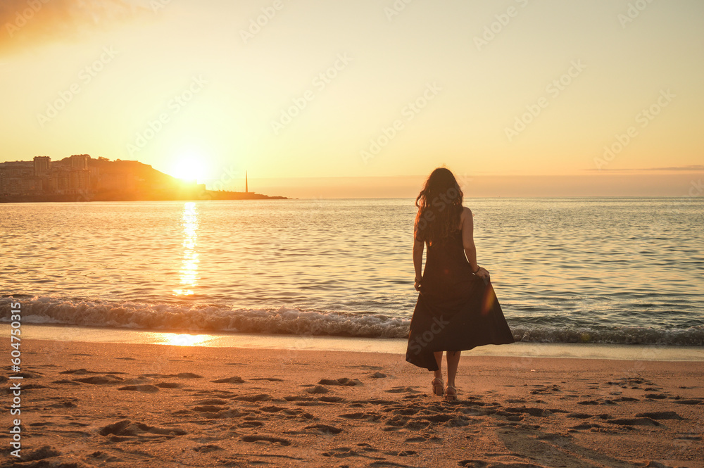 woman walking on the beach with dress in a sunset