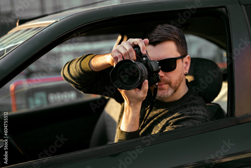 Fototapet Man detective or agent taking photos from the car, wearing modern sunglasses