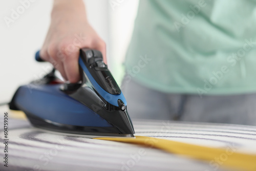 Male person irons yellow tie with hot steam in morning