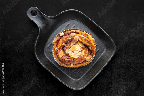 cinnamon almond danish roll in black pan on dark grey texture background