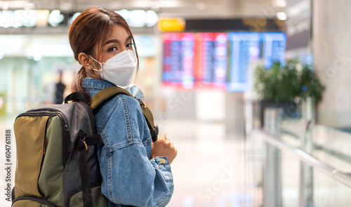 Young asian woman traveler in quarantine for coronavirus wearing surgical mask face protection with backpack flight travel before long travel vacation flight at International terminal airport