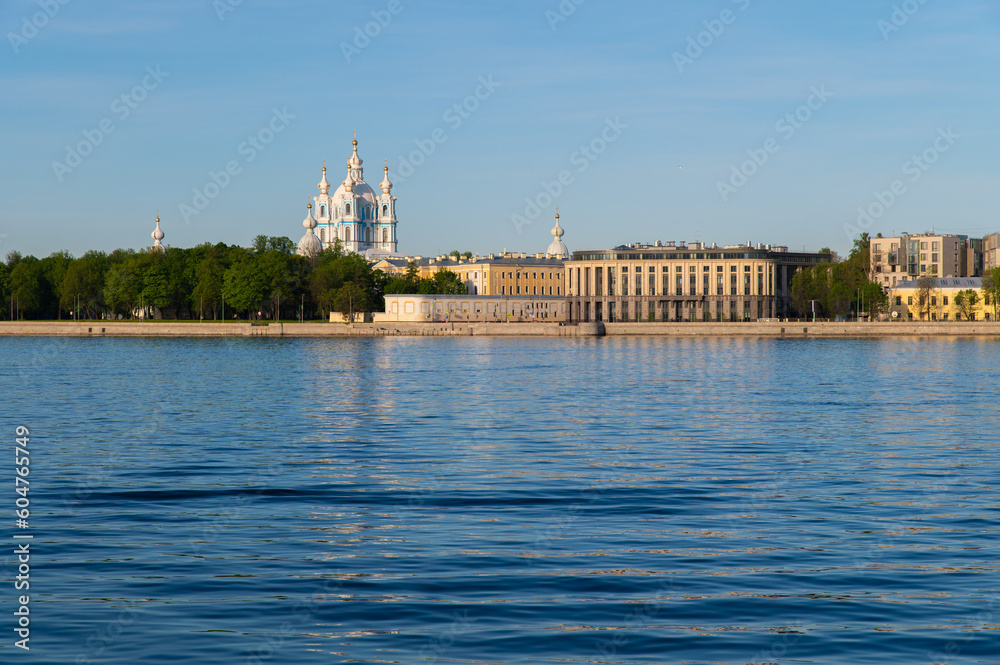 Fototapeta premium Saint-Petersburg, Russia. May 20, 2020: Granite city embankment with a park and a cathedral illuminated by the morning sun