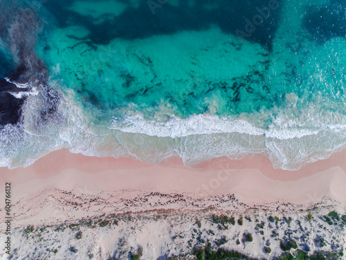 Aerial view of pink sandy beach with waves. Sunny day in summer with transparent tropical blue water. Summer seascape beautiful waves, blue sea water on a sunny day. Top view from drone. Sea aerial © Matt