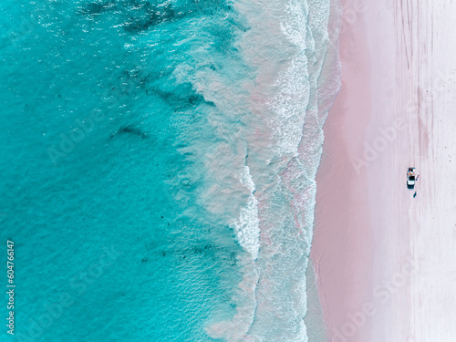 Aerial view of beautiful tropical turquoise ocean sea waters with shallow waves on pink beach. Vibrant bright sunny day in summer wallpaper. Sandy pink sand beach, Seascape background. Coastal