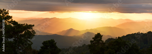Panoramic picture of a beautiful sunset over the mountains. wonderful springtime landscape in the mountains. grassy field and rolling hills.