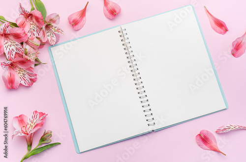 The notebook surrounded by pink Alstroemeria flowers and petals © Olena Rudo