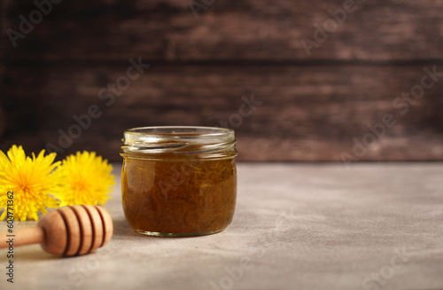 Dandelion flower jam in a glass jar on a wooden background