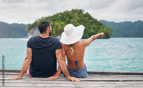 Ocean, vacation and couple together on deck, dock or sitting on boardwalk to relax and enjoy the sea, water or landscape. People, man and woman on holiday, summer travel or tropical date in Bali