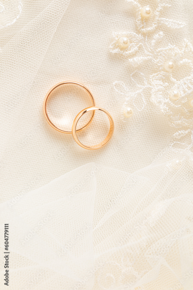 A chic vertical feed for two gold wedding rings on a beige satin background and lace tulle. space for text. layout design. A chic vertical feed for two gold wedding rings on a beige satin background and lace tulle. space for text. layout design.
