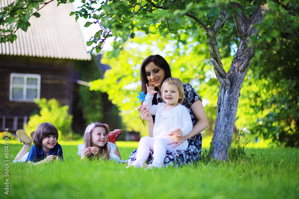 Obraz premium Young large family on a summer morning walk. Beautiful mother with children is playing in the park.