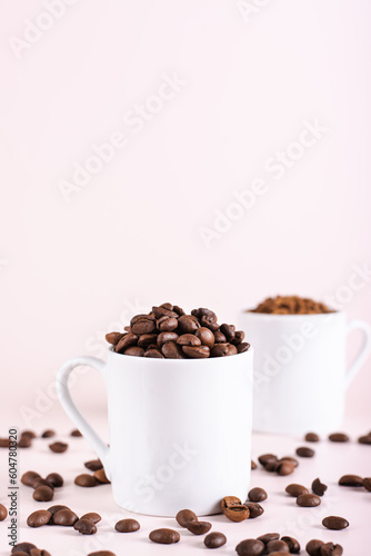 Roasted coffee beans and instant coffee in cups on pink background vertical view