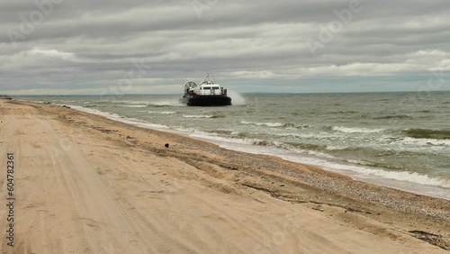 The coastguard hovercraft moves quickly along the beach. Patrolling the coast. The hovercraft moves across the sea. Slow motion