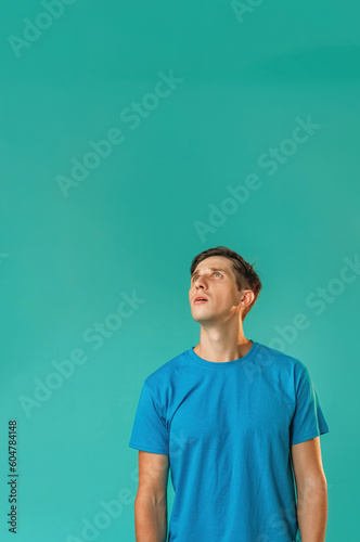 Curious man. Interesting advertising. Important information. Thoughtful concentrated guy in blue reading promotional text focused expression isolated on turquoise empty space background. © golubovy