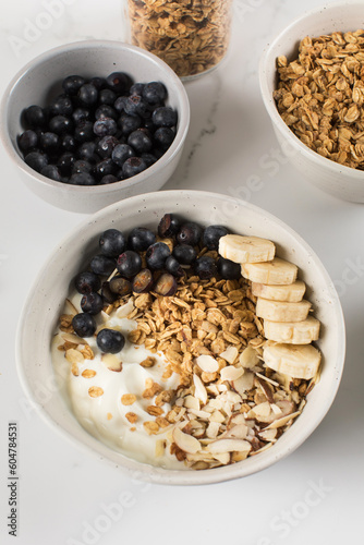 Homemade granola with Greek yogurt, almonds, blueberries and banana in a bowl. 