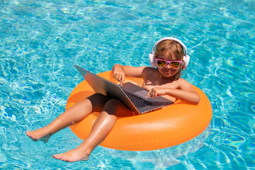 Work outside concept. Child working on laptop computer at poolside swimming pool. Summer online technology. Traveler relaxing on tropical sea beach in summer holidays vacation.