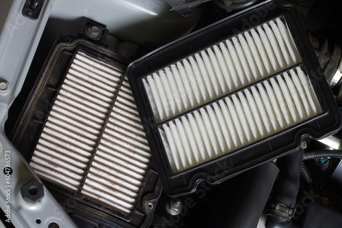 Old and new air filters in the engine compartment of the car. Replacing a dirty air filter.
