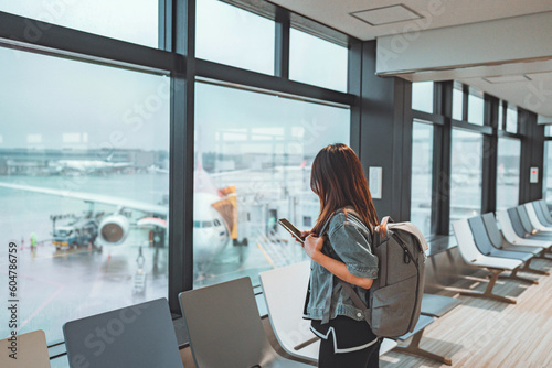 Happy asian tourist woman using mobile smartphone with backpack traveling between waits for flight in Airport Terminal, Browse Internet, flight check in, Tourist journey trip concept