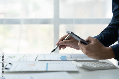 Copy space, banner, panorama. Businessman working on laptop, using mobile phone at office, analyzing business documents with graphs. Financial charts, market reports. Business data analysis concept.