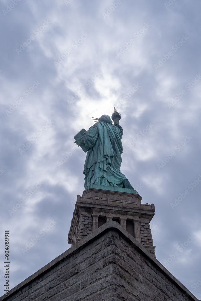 Back of the statue of liberty against a cloudy sky