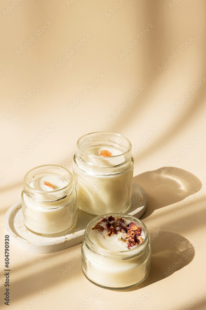 Handmade candle from paraffin and soy wax in glass with wooden wick and dry herbal isolated on pastel beige background. Flat lay, top view, copy space Handmade candle from paraffin and soy wax in glass with wooden wick and dry herbal isolated on pastel beige background. Flat lay, top view, copy space