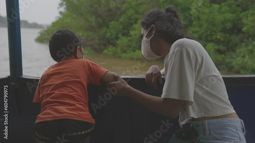 A little boy and a young girl are sitting on a boat enjoying a sea trip on an island. photo