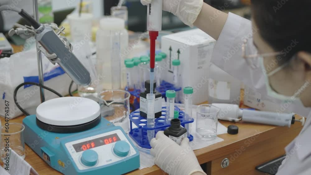 Chemistry research scientist uses a micropipette to mix chemicals to