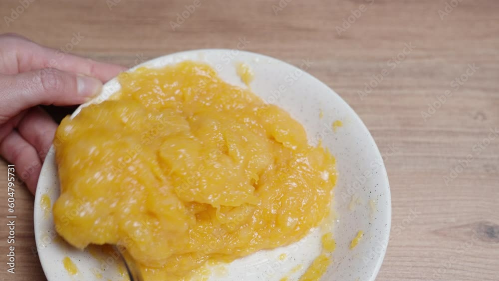 From above, a woman is stirring the orange compote filling for the cake. From above, a woman is stirring the orange compote filling for the cake.