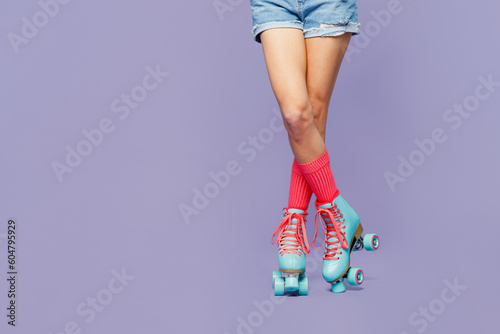 Close up cropped female legs in rollerblades rollers shorts isolated on pastel plain light purple violet wall background studio. Summer sport lifestyle leisure concept. Copy space advertising mock up.