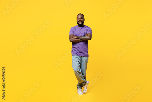 Full body fun young man of African American ethnicity he wear casual clothes purple t-shirt hold hands crossed folded look camera isolated on plain yellow background studio portrait Lifestyle concept