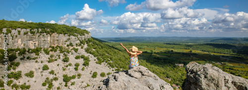 Fotografie Woman with dress sitting on a mountain peak looking at view of languedoc landsca