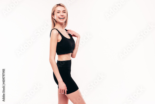Young beautiful smiling blond female in summer black cycling shorts costume clothes. Sexy carefree woman posing on white in studio. Positive model having fun. Cheerful and happy