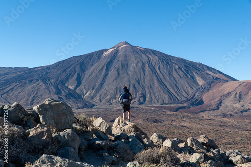 Man on rock with view on La Canada de los Guancheros dry desert plain and volcano Pico del Teide, Mount Teide National Park, Tenerife, Canary Islands, Spain, Europe. Hiking to Riscos de la Fortaleza photo