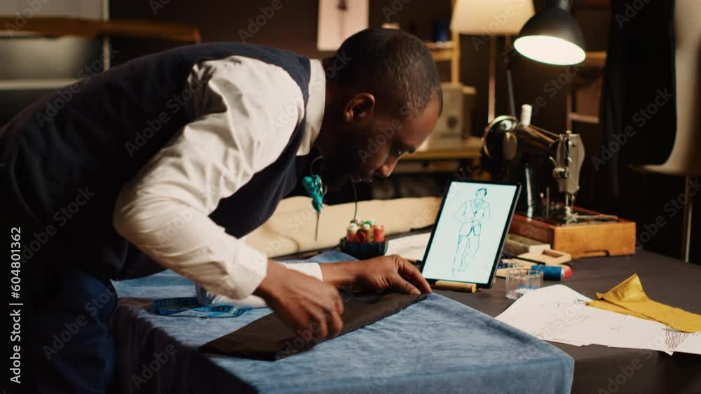 Craftsman measuring fabric in atelier, working on new custom made item with sewing tools and pins. Couturier designing fashion model with professional tailoring equipment. Handheld shot.