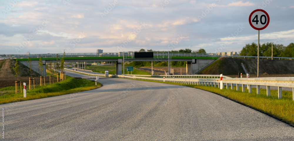 Newly constructed highway,asphalt,guardrails.In the background spring landscape - obrazy, fototapety, plakaty 