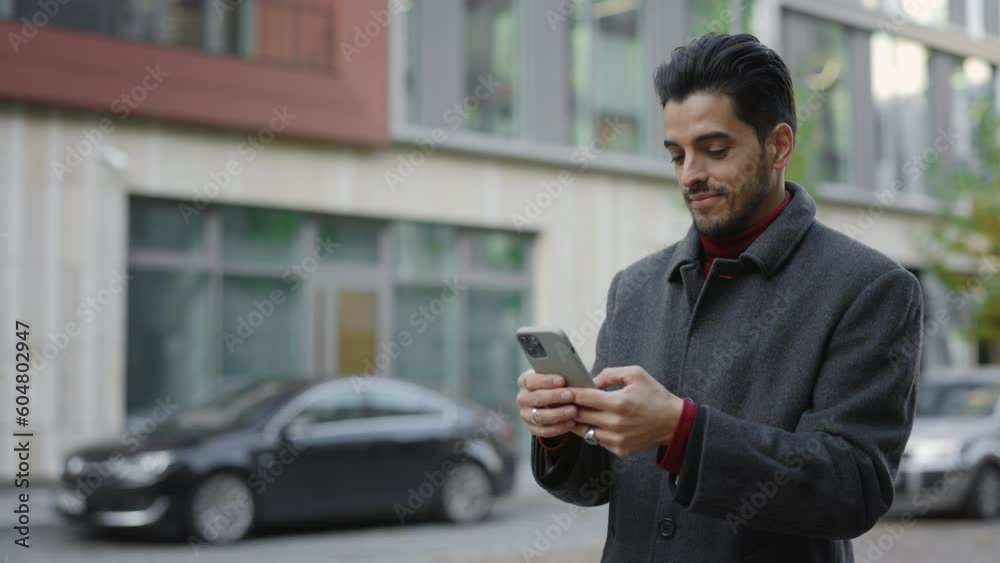 Smiling Multi Ethnic Businessman Texting with Clients, Using Smartphone Standing Outside. Male manager Texting, Communication via Phone. Business. Social Network. People and Technology Concept Smiling Multi Ethnic Businessman Texting with Clients, Using Smartphone Standing Outside. Male manager Texting, Communication via Phone. Business. Social Network. People and Technology Concept