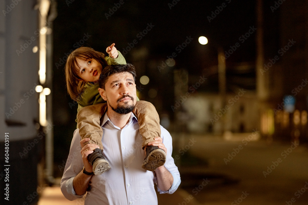 Thoughtful father carrying son on shoulders at night Thoughtful father carrying son on shoulders at night