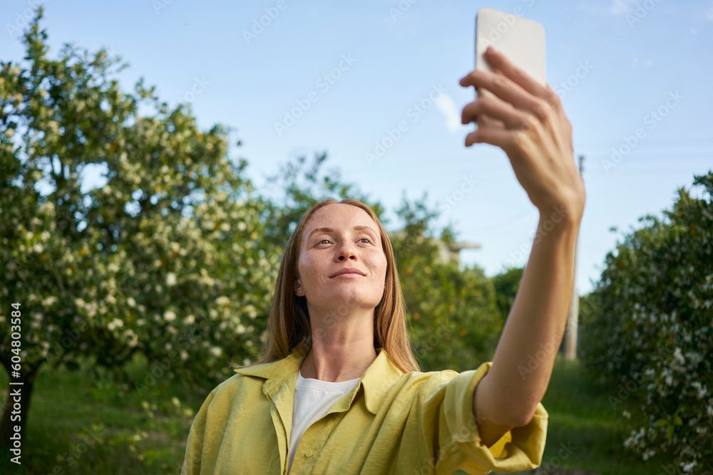 Woman taking selfie through smart phone in garden Woman taking selfie through smart phone in garden