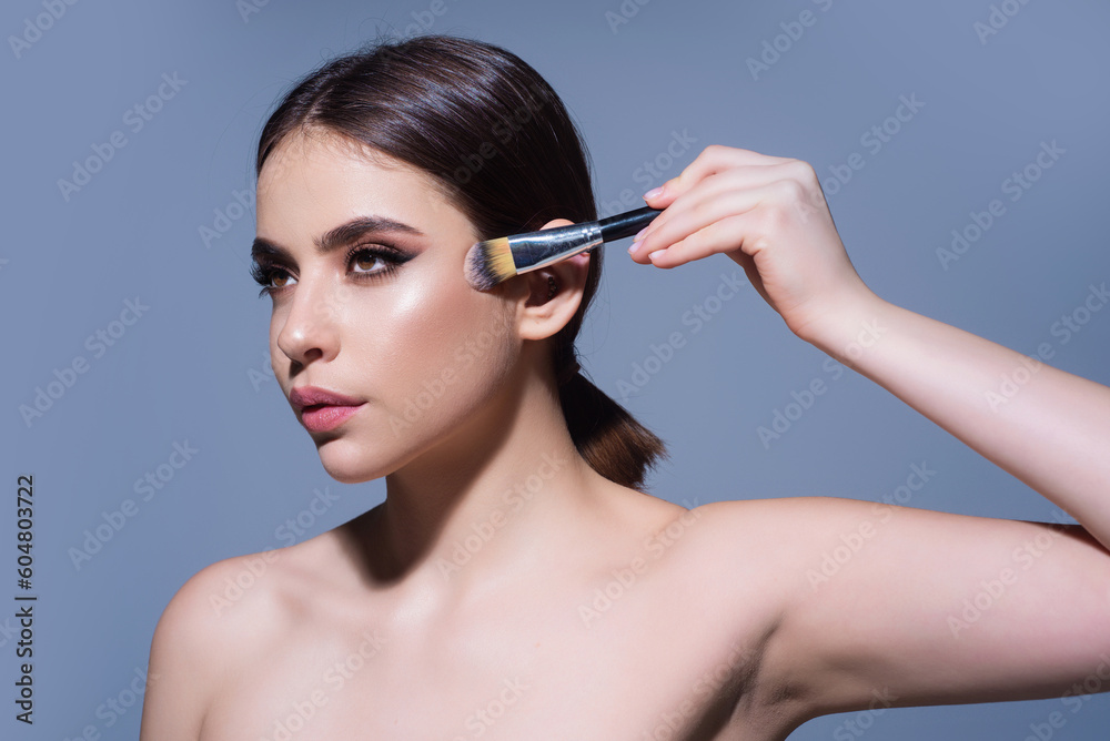 Beautiful young woman apply powder on face. Beauty Makeup. Portrait of female model with cosmetic brush. Perfect soft skin and natural makeup. Applying powder blush highlighter, foundation tone.