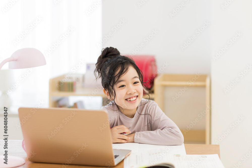 自宅でパソコンを見ながら勉強する女の子 自宅でパソコンを見ながら勉強する女の子