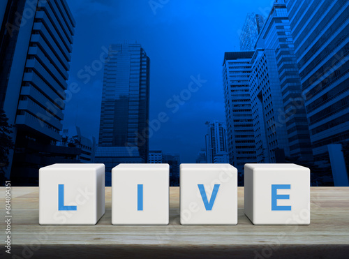 Live letter on white block cubes on wooden table over modern office city tower and skyscraper, Technology broadcasting communication concept
