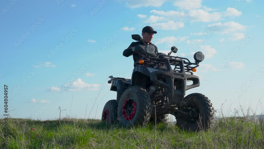 a man is sitting on a quad bike,a man on a mountain on a quad bike admires the landscape a man is sitting on a quad bike,a man on a mountain on a quad bike admires the landscape