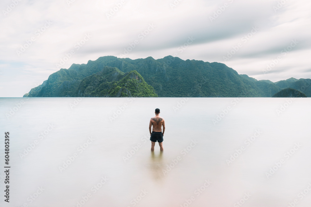 Carefree man looking at mountains standing in sea Carefree man looking at mountains standing in sea